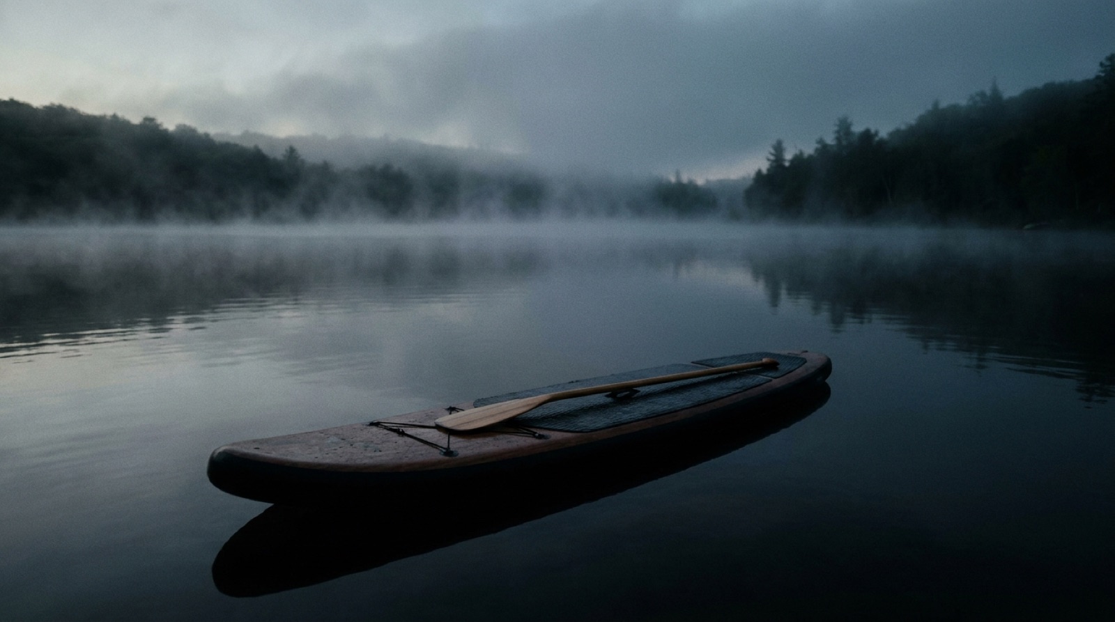 A paddleboard on still water at first light